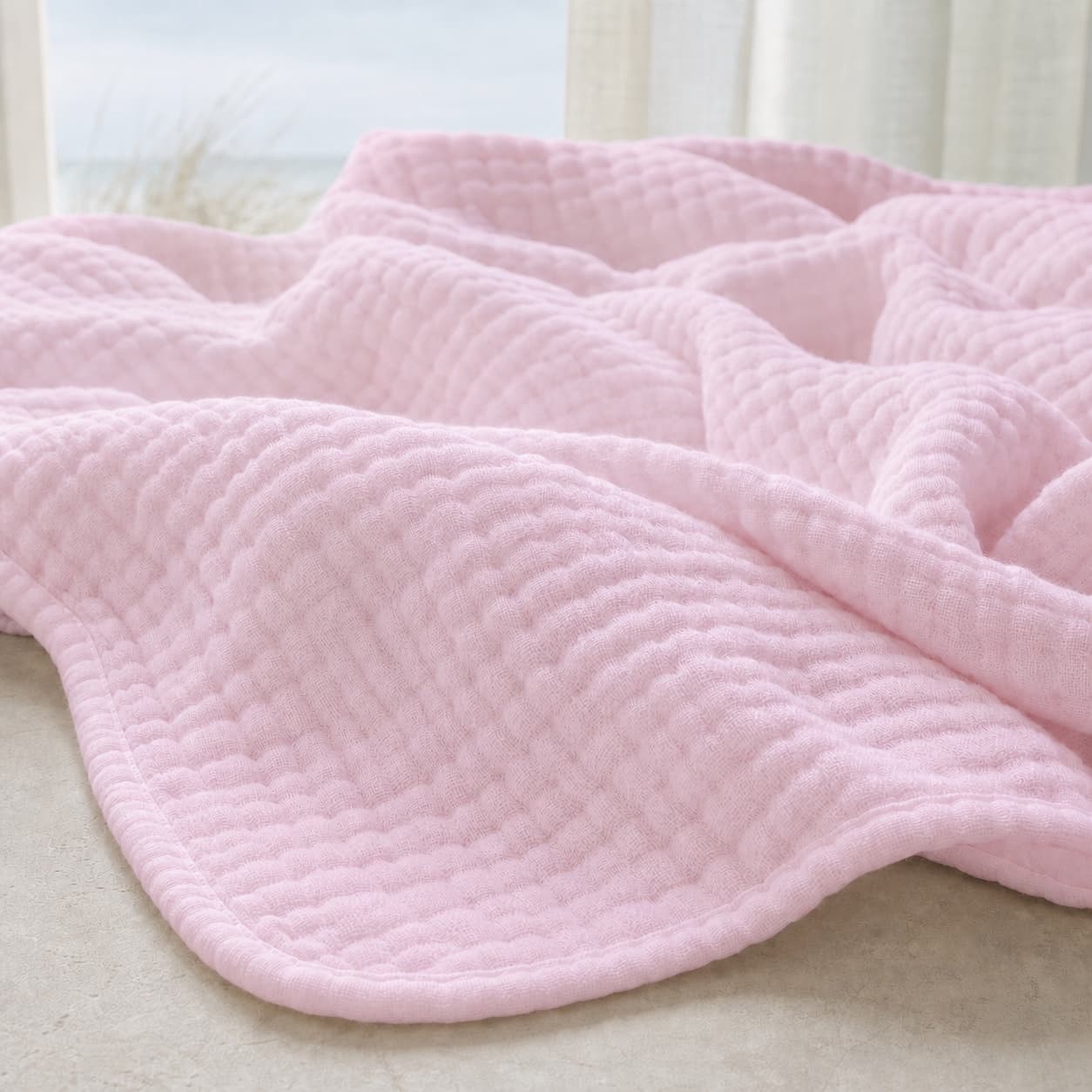 Close-up of the pale pink texture of a lightweight muslin blanket