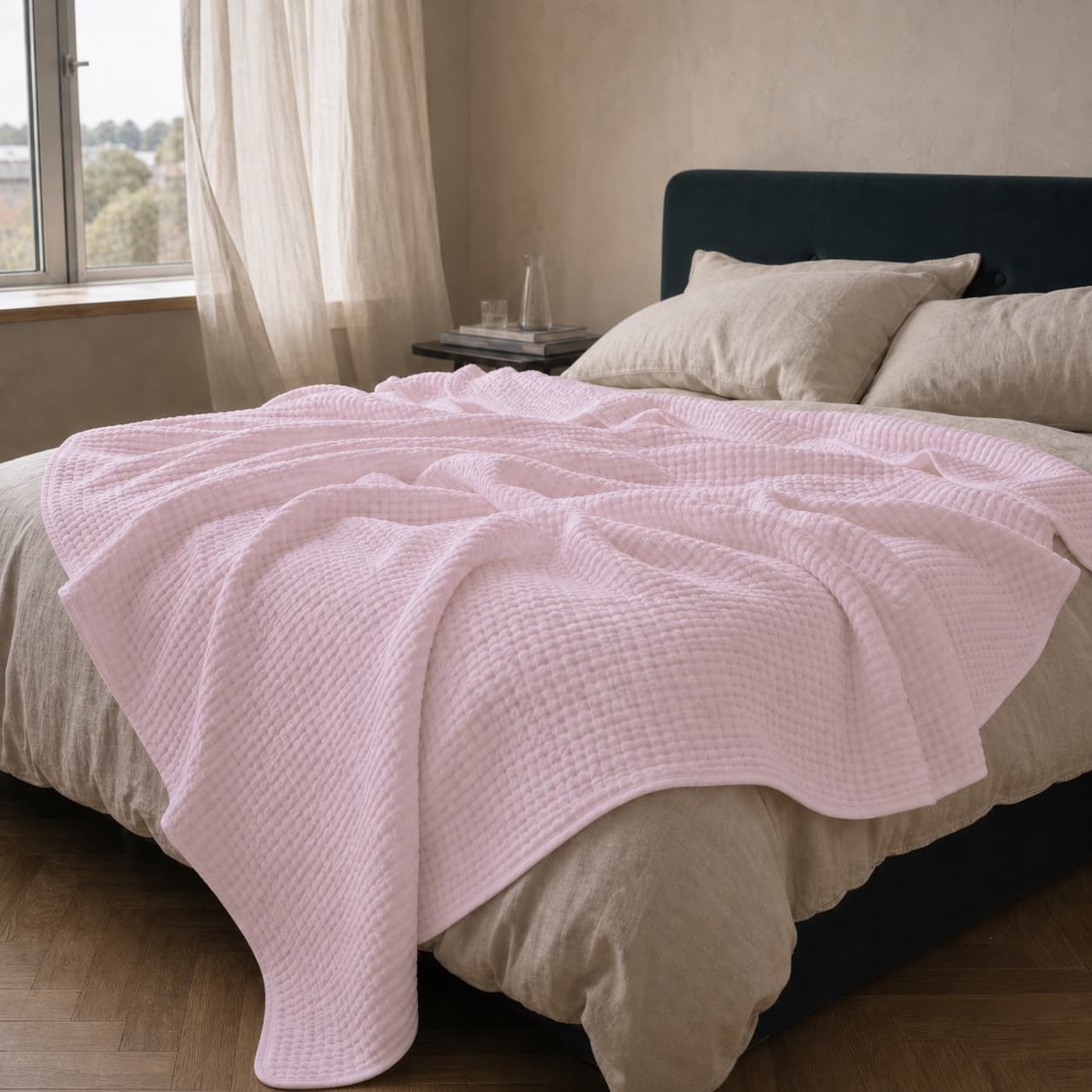 Lightweight pale pink muslin blanket spread across a bed