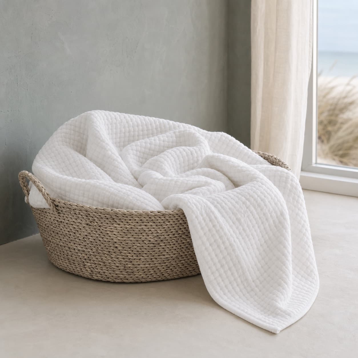 White lightweight muslin blanket in a basket by a window